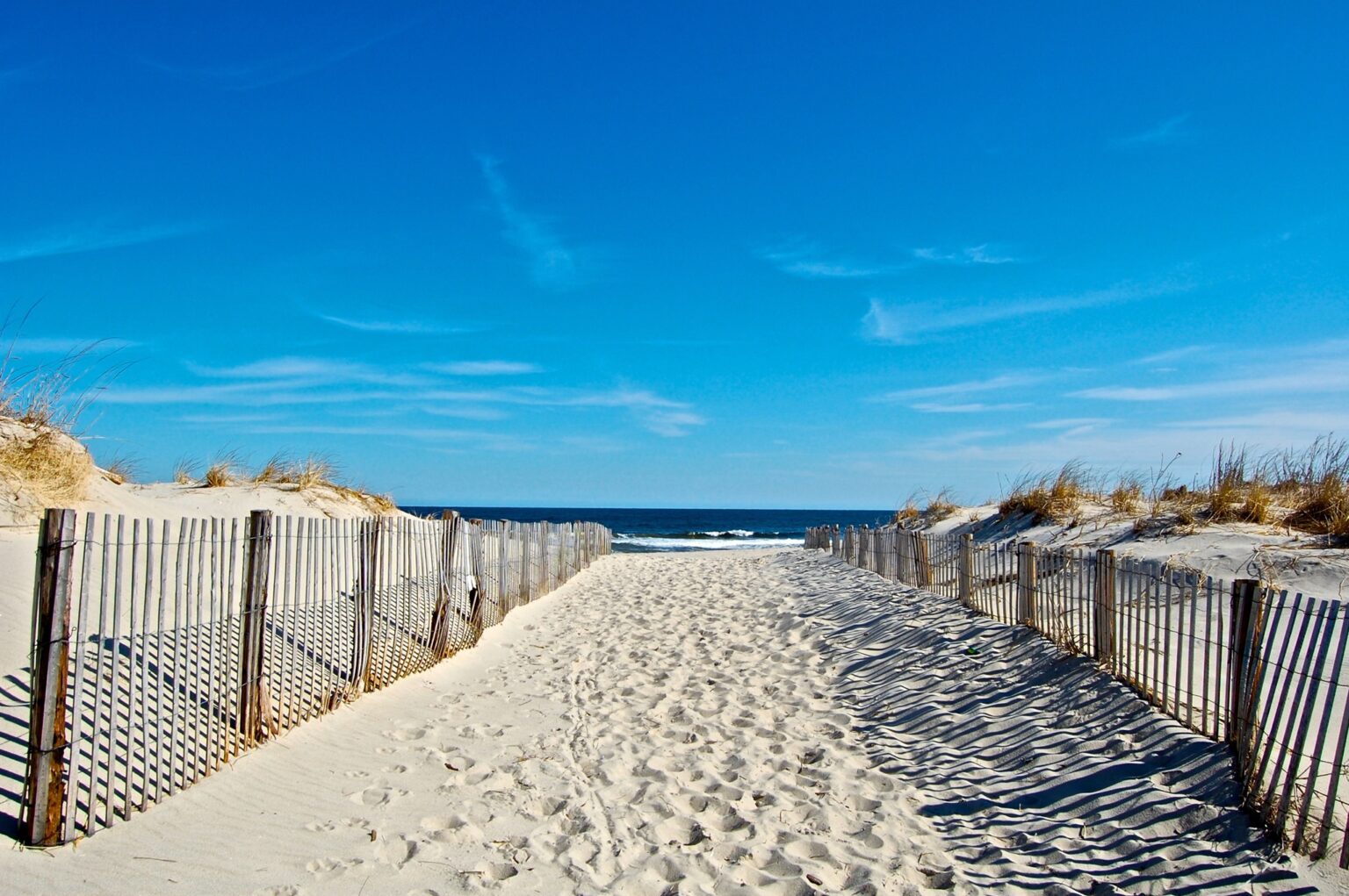 Sandy beach path lined with wooden fences leading to the ocean on Long Island, New York